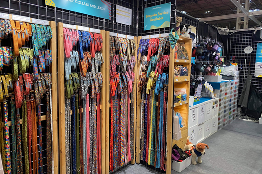 Large selection of handmade brightly coloured and patterned fabric dog collars and leads displayed at an indoor retail show