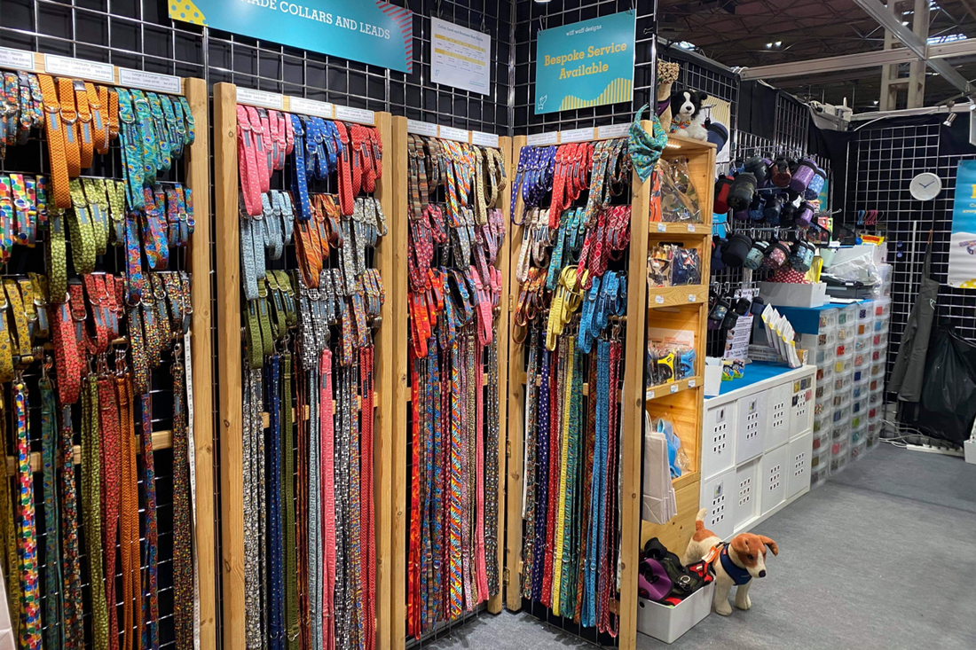 Large selection of handmade brightly coloured and patterned fabric dog collars and leads displayed at an indoor retail show