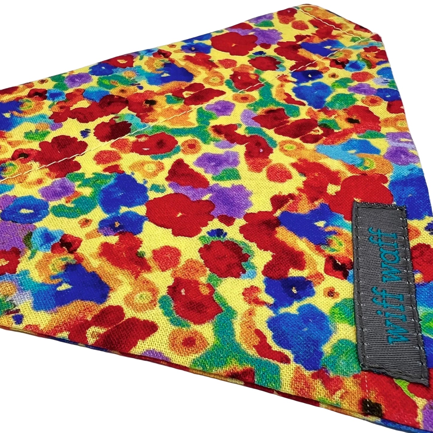 A dog collar bandana in 100% cotton fabric made up of a light yellow background adorned with irregular, abstract blotches in red, blue, green, purple, and occasional orange.