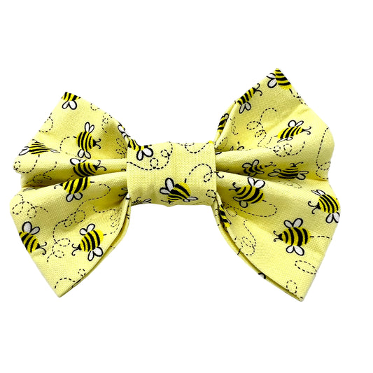Pale yellow bow tie with bee pattern all over it.