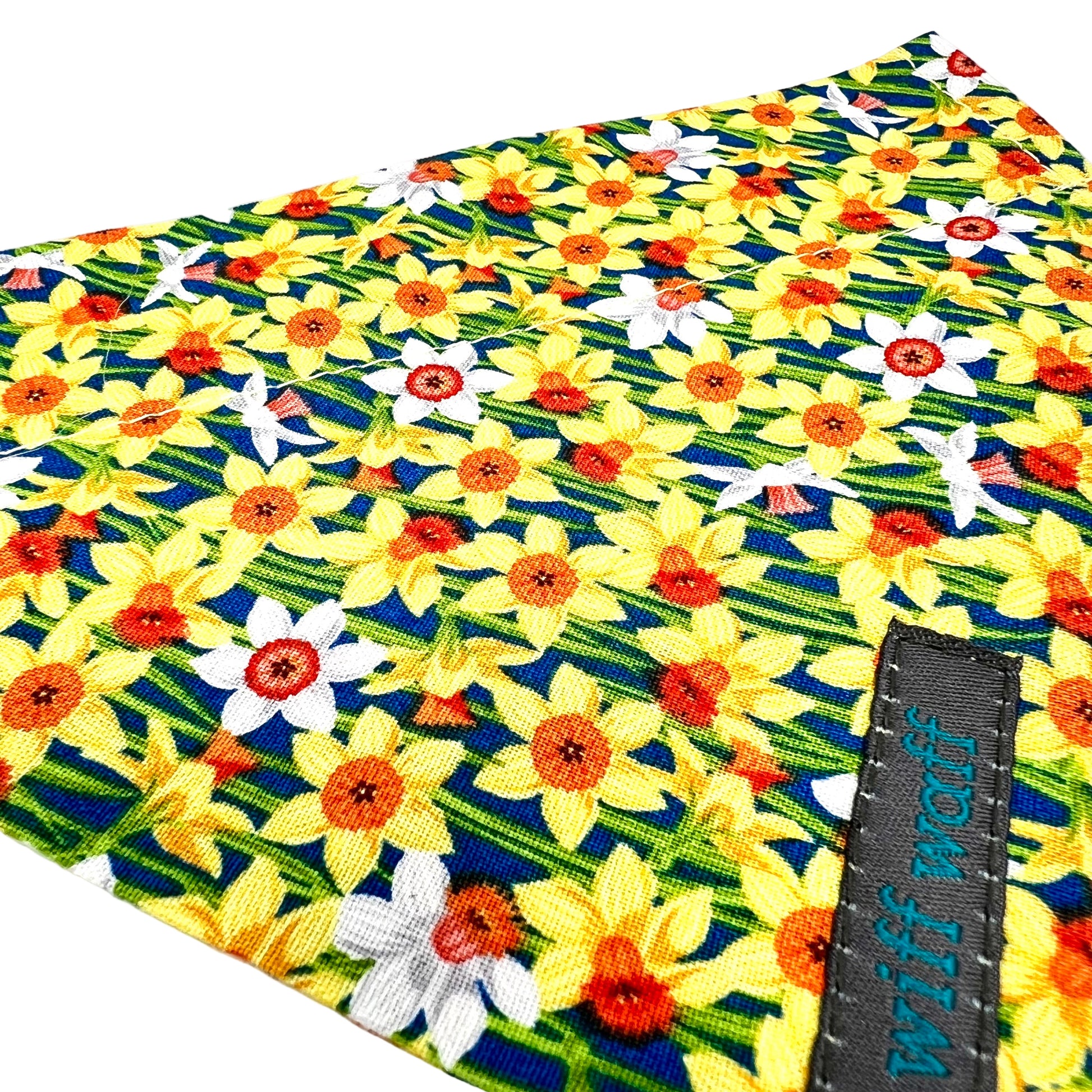 Yellow and white floral daffodil patterned dog bandana with a visible brand tag on a blue background