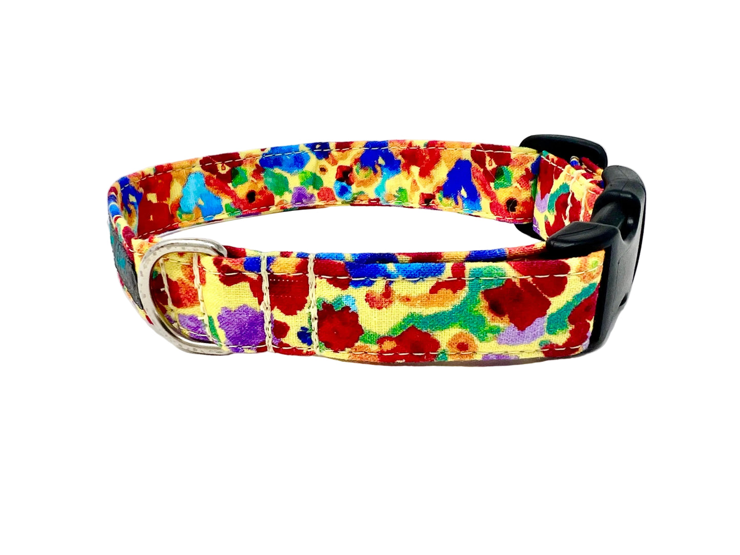 Colourful dog collar set against a light yellow background adorned with irregular, abstract blotches in red, blue, green, purple, and occasional orange. 