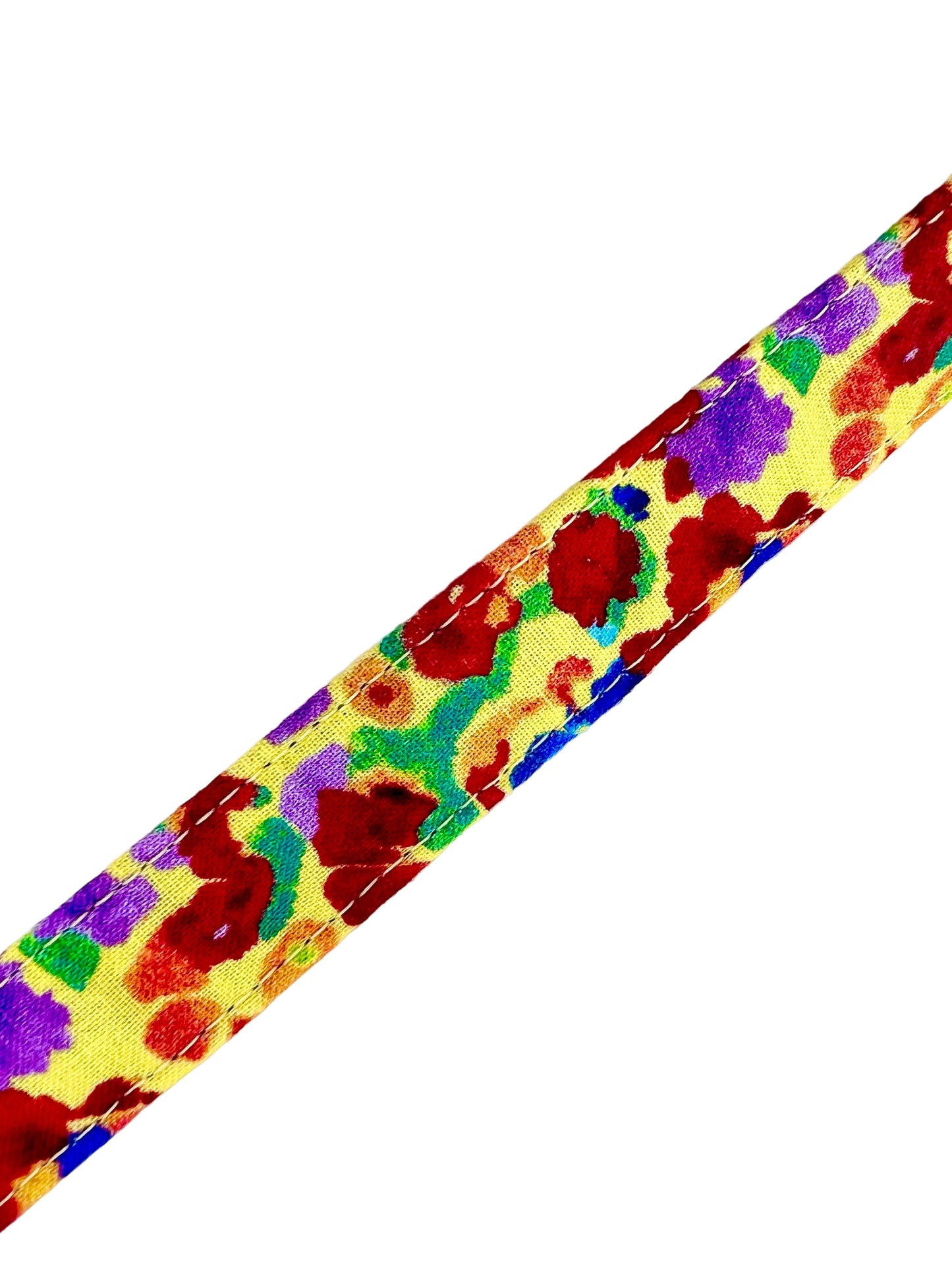 Colourful dog collar set against a light yellow background adorned with irregular, abstract blotches in red, blue, green, purple, and occasional orange. 