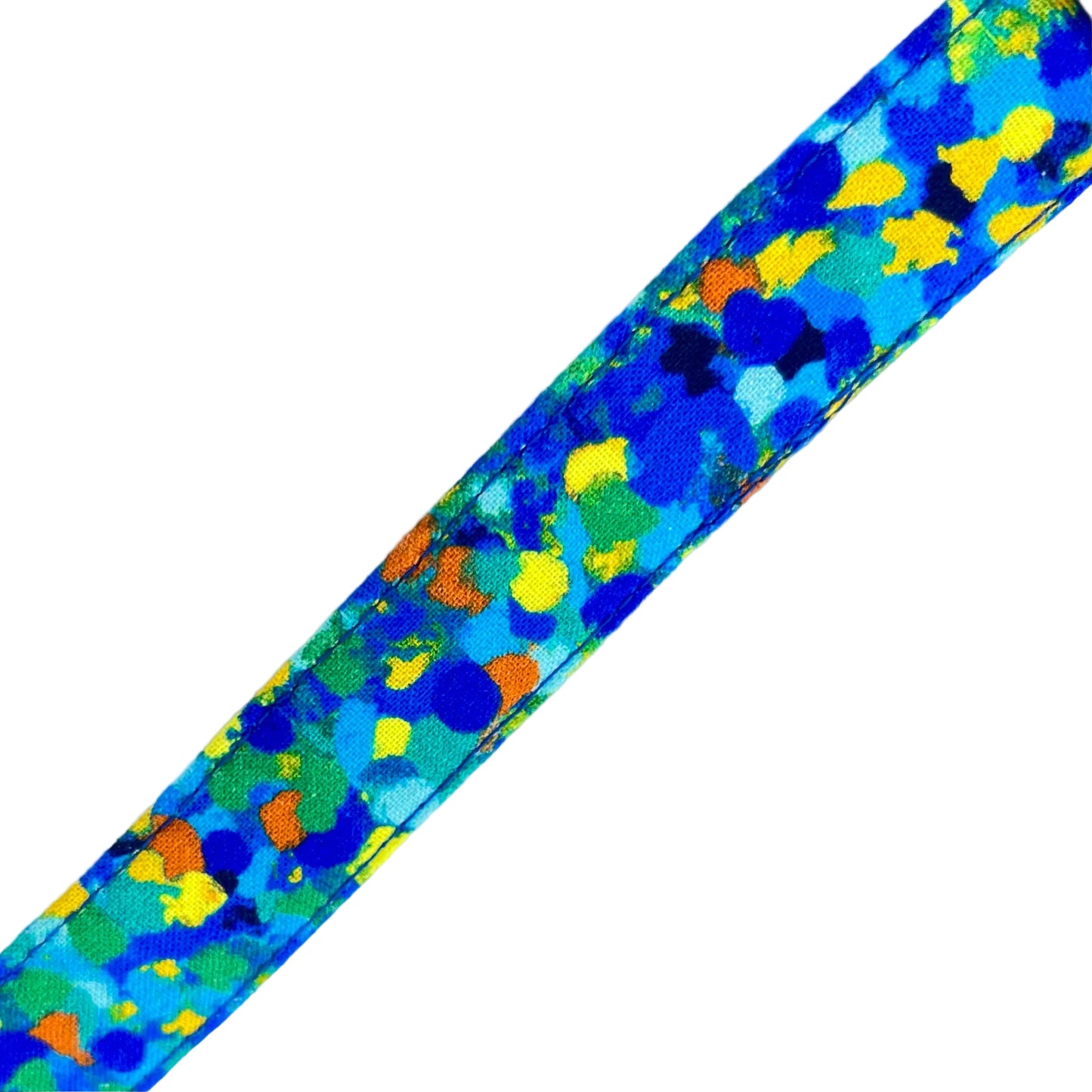 Dog collar with splattered dots of blues and a touch of yellow, green and orange.