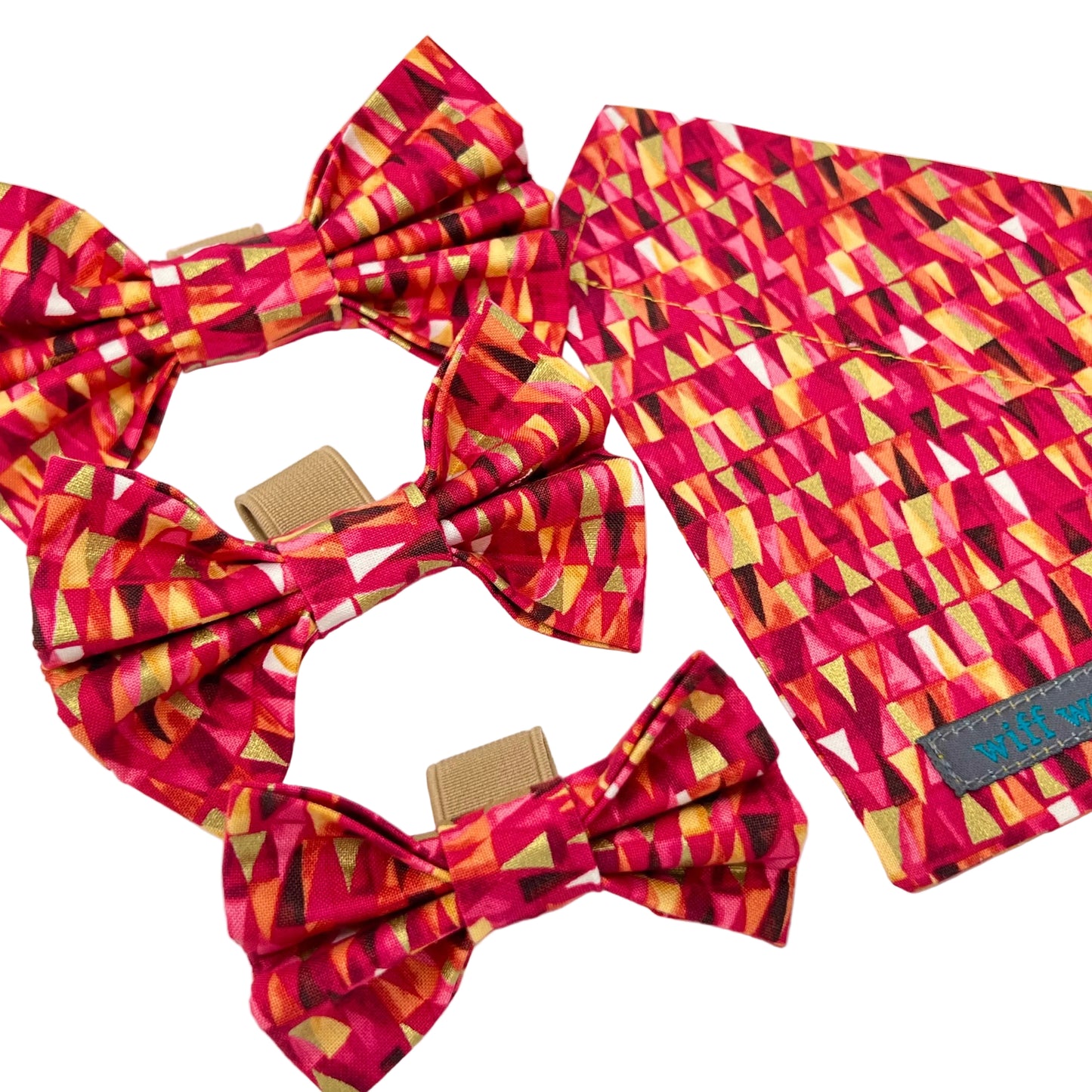 A dog collar bandana featuring pink and red hues accented with gold metallic touches alongside 3 dog bows in the same fabric