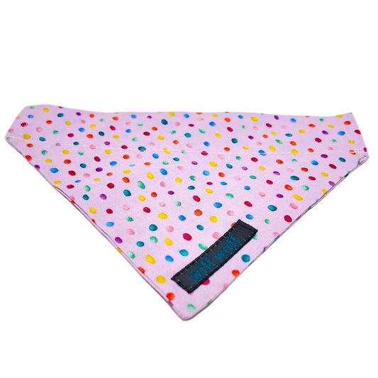 a dog bandana which has a pink back ground with tiny colourful rainbow bubbles scattered across it.