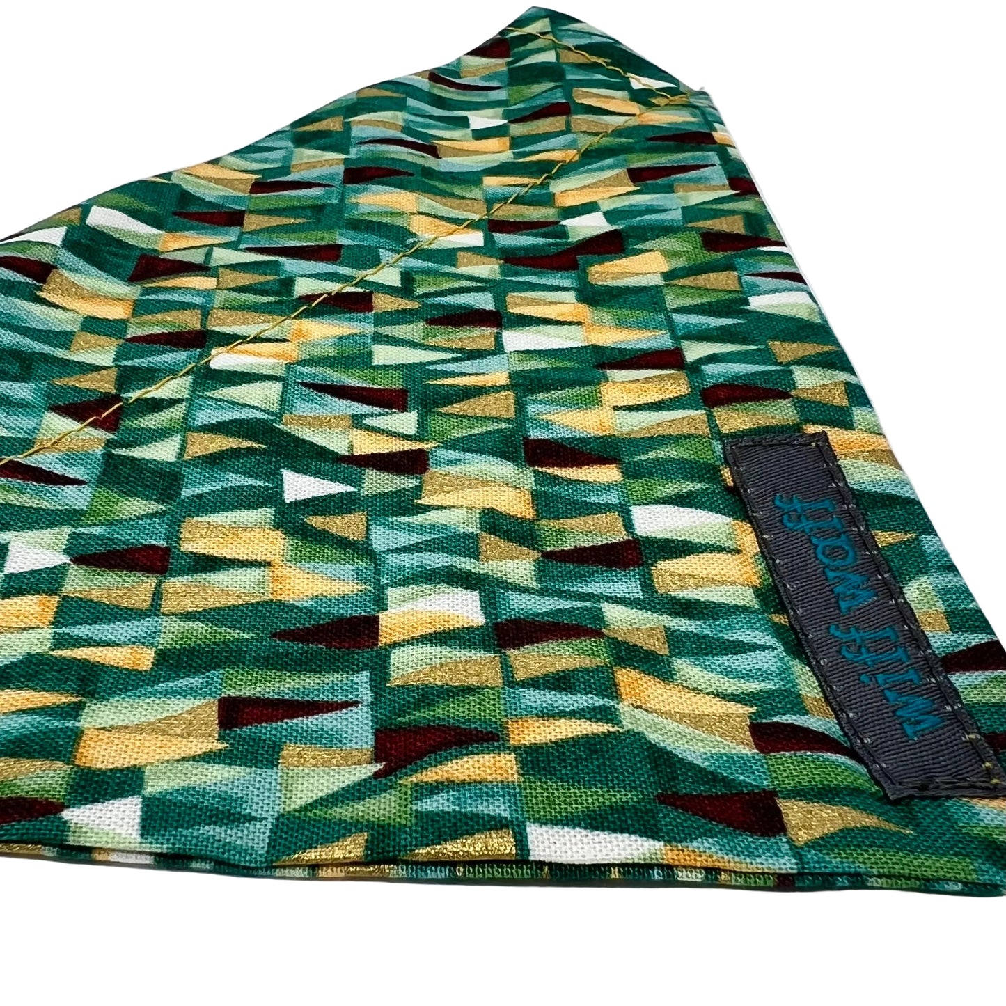 a dog collar bandana in fabric iwith shades of greens and has gold metallic highlights.