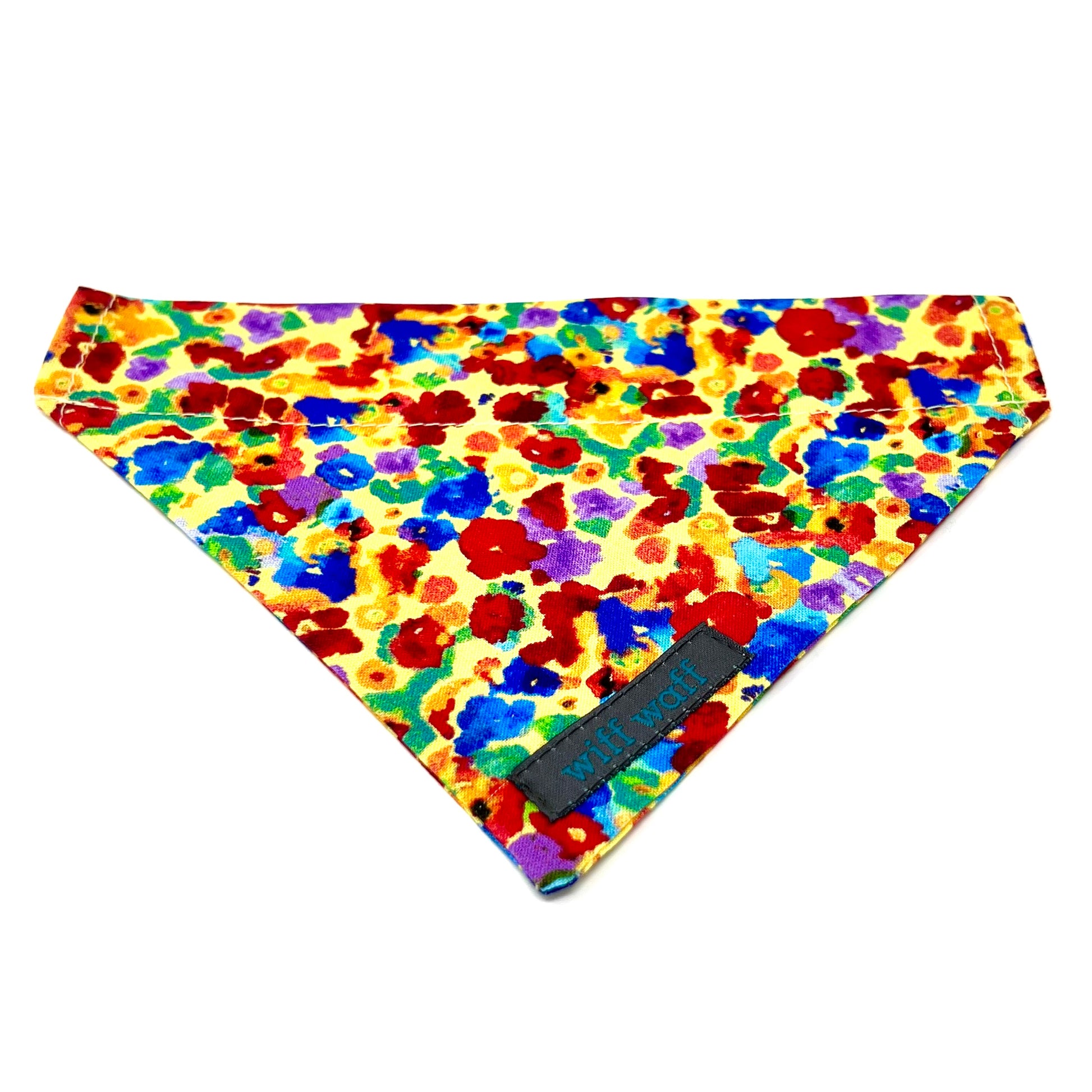 A dog collar bandana in 100% cotton fabric made up of a light yellow background adorned with irregular, abstract blotches in red, blue, green, purple, and occasional orange. 