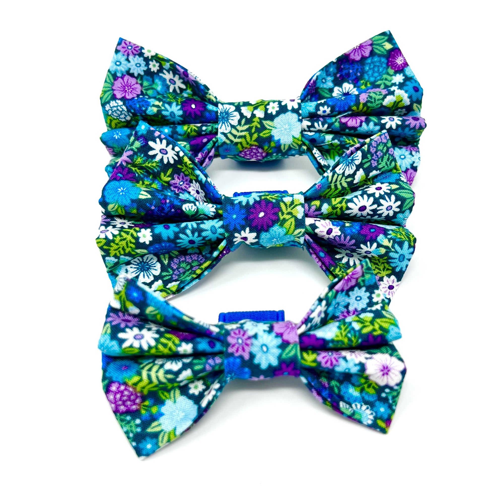 colourful dog bows featuring a vibrant floral design in shades of blue, violet, green and white. sizes small, medium and large.