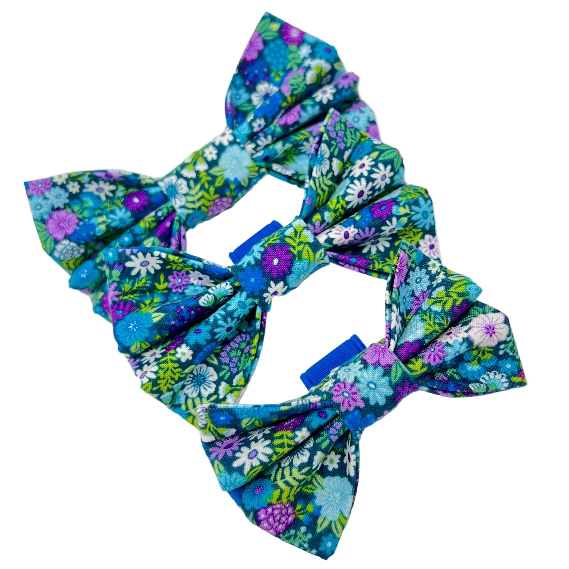 colourful dog bows featuring a vibrant floral design in shades of blue, violet, green and white. sizes small, medium and large.