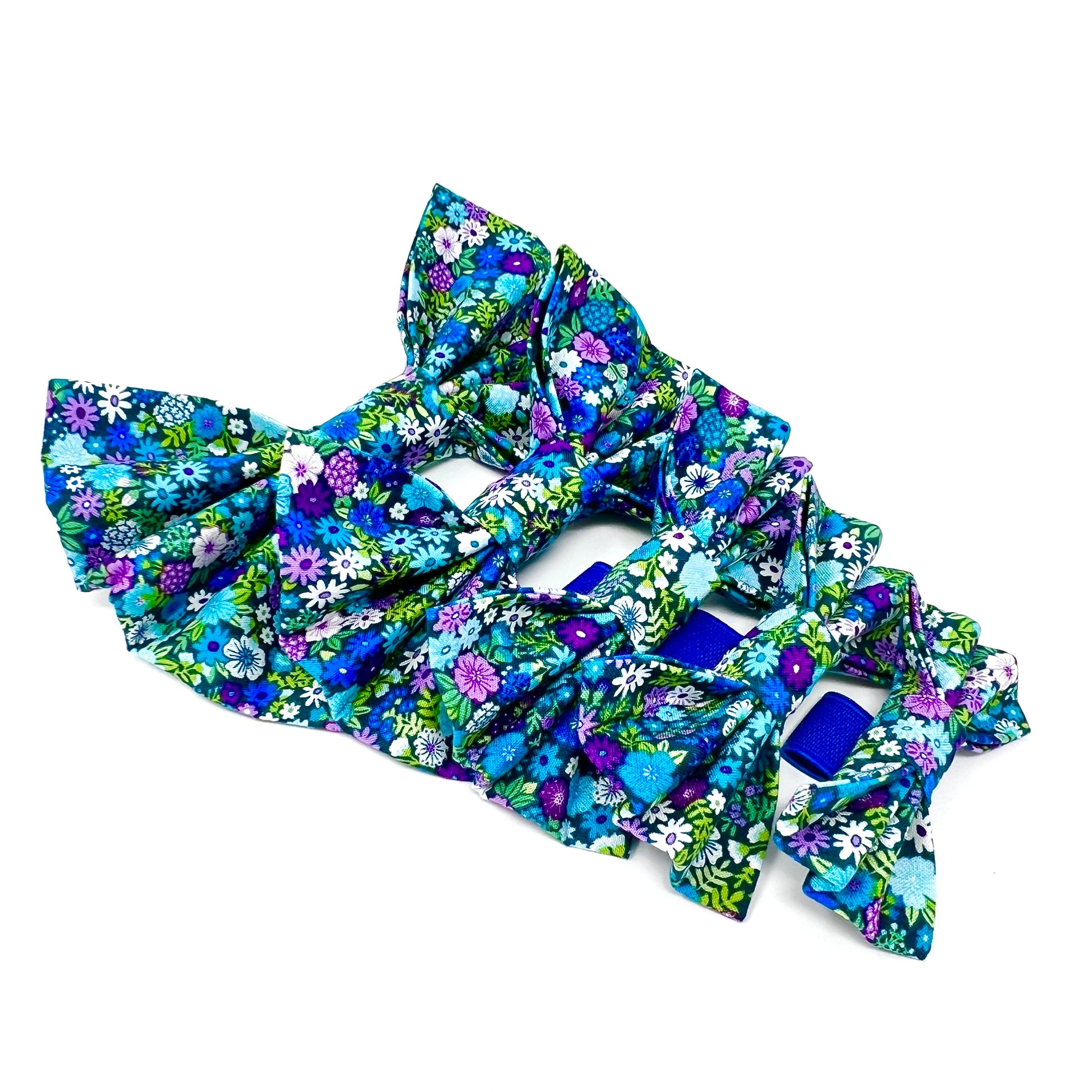 Five colourful dog bows featuring a vibrant floral design in shades of blue, violet, green and white. Sizes small. medium, large, large plus and small XL.