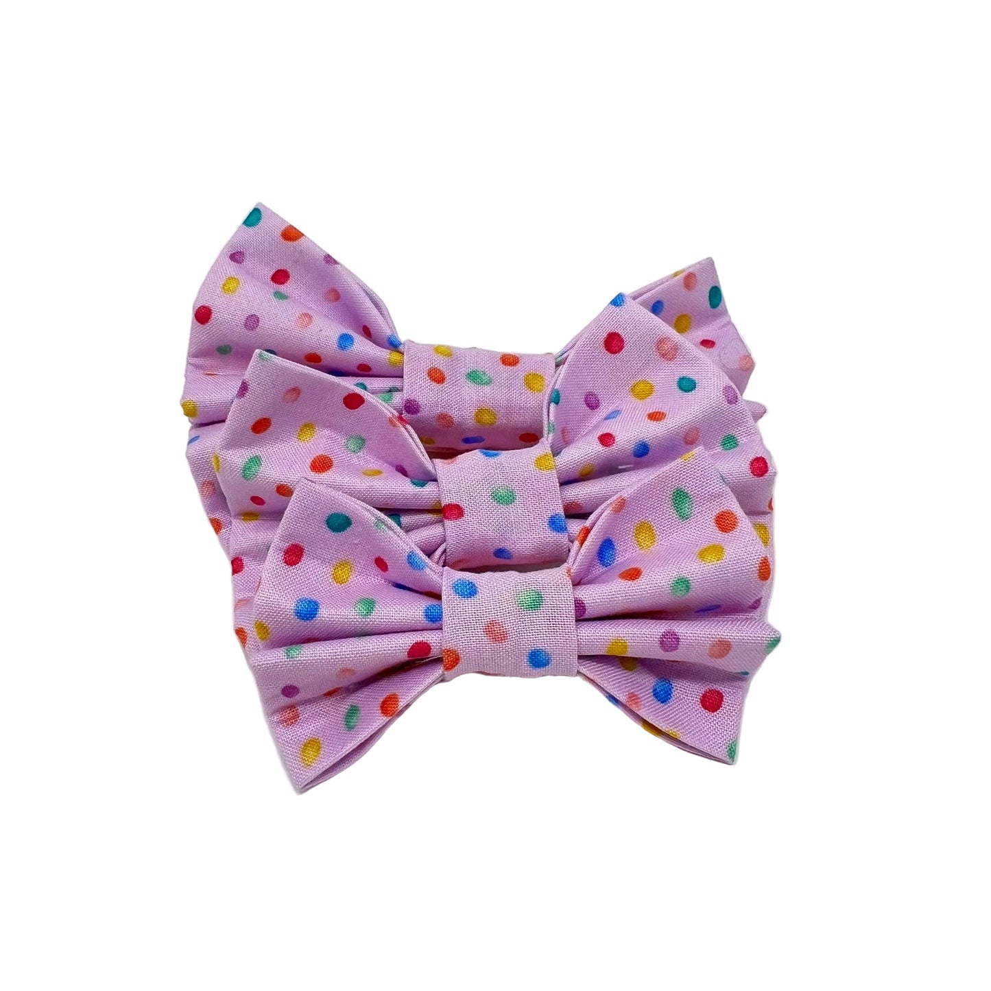 three dog bows with a pink back ground and tiny colourful rainbow bubbles scattered across it. feminine . sizes small, medium and large.